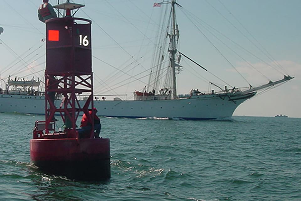a current buoy with a sailing ship in the background