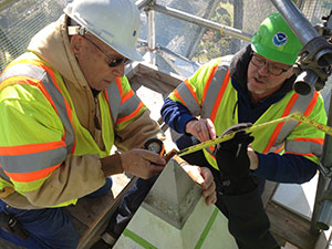 National Geodetic Survey crew members Don Breidenbach and Kendall Fancher take measurements to prepare for the construction of an adapter which will hold various survey instruments at the peak of the Washington Monument.