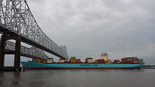 Large container ship passing under a bridge on the Mississippi River.