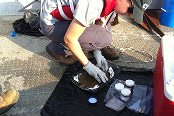A scientist with the response transfers a sediment sample from the Mississippi River to collection jars for analysis following a collision and oil spill near Columbus, Kentucky