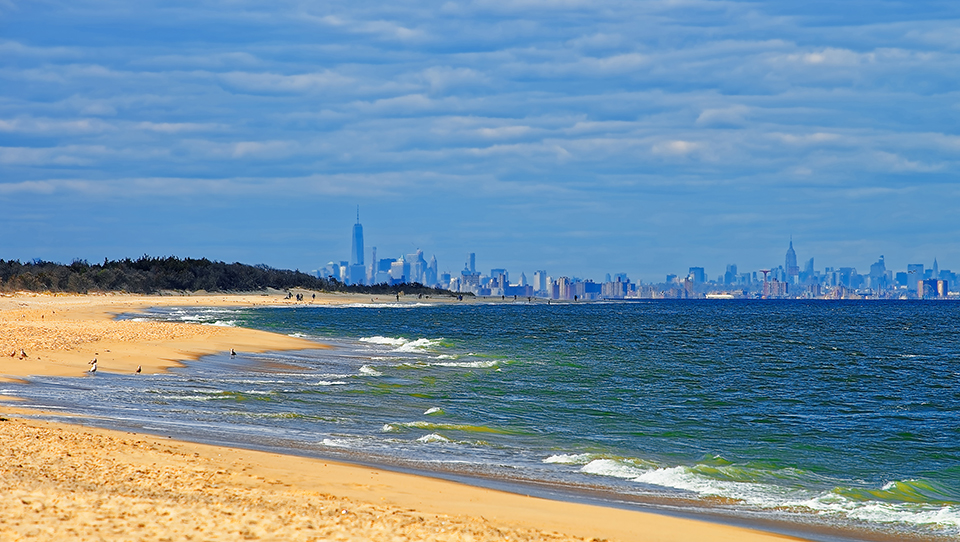 A New Jersey beach with a view of the New York City skyline.