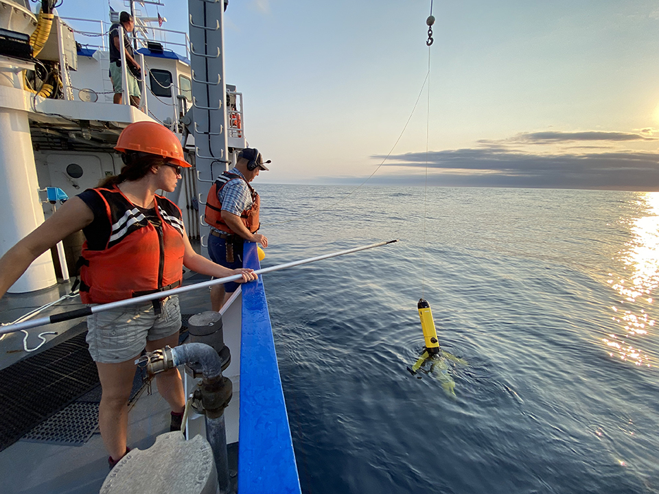 The crew on a research vessel working to recover a glider from the water.