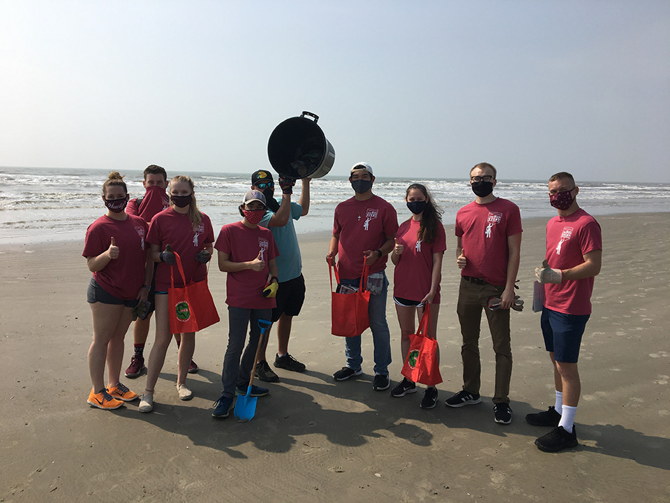 Group of college students on a beach after a beach cleanup.