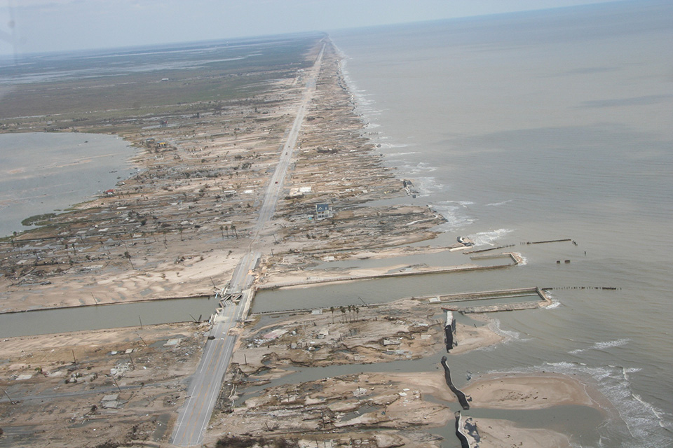 An aerial view of damaged property and land along the coast.