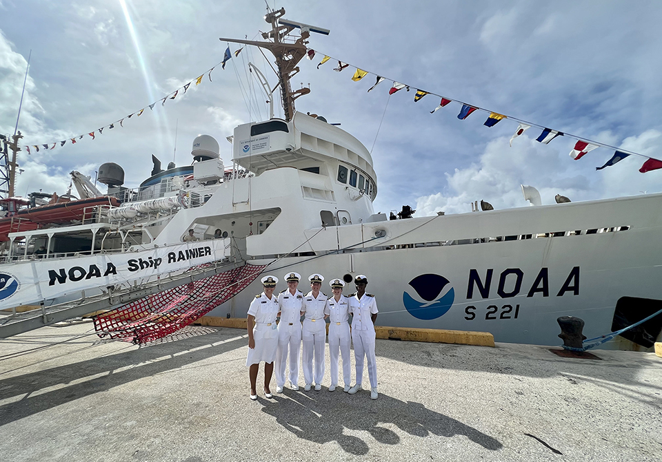Five female officers in uniform in front of a NOAA ship.