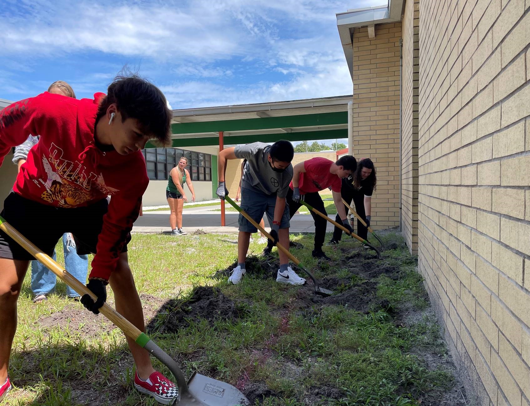 Students at Seminole High School begin clearing areas for a wildflower garden.