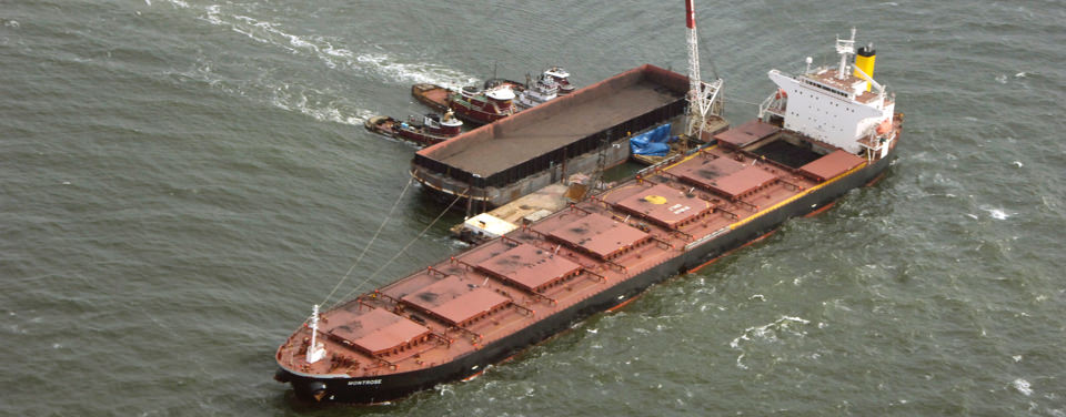 A lightering barge being positioned next to the freighter