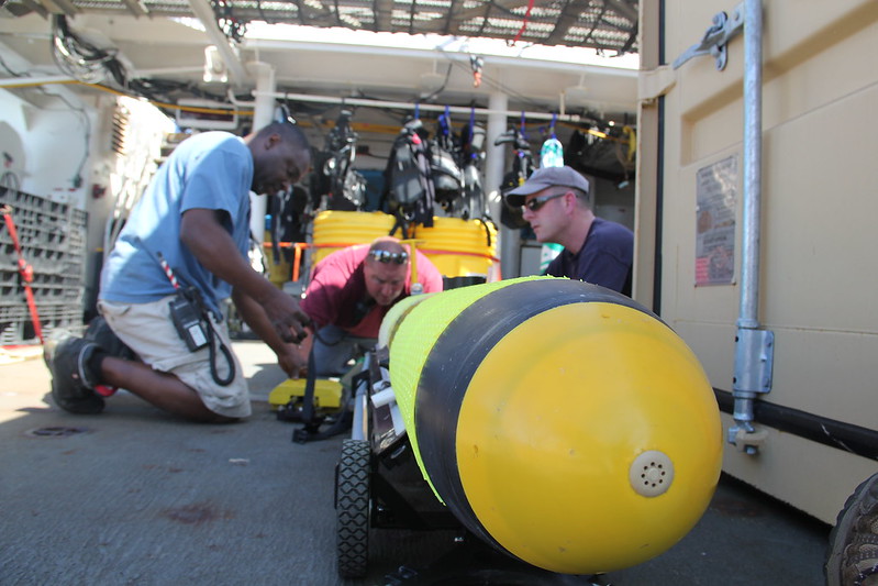 NOAA Ship Nancy Foster's Chief Boatswain Greg Walker and Bosun Group Leader James Best work with scientist Tim Battista to prepare the ocean glider for launch.