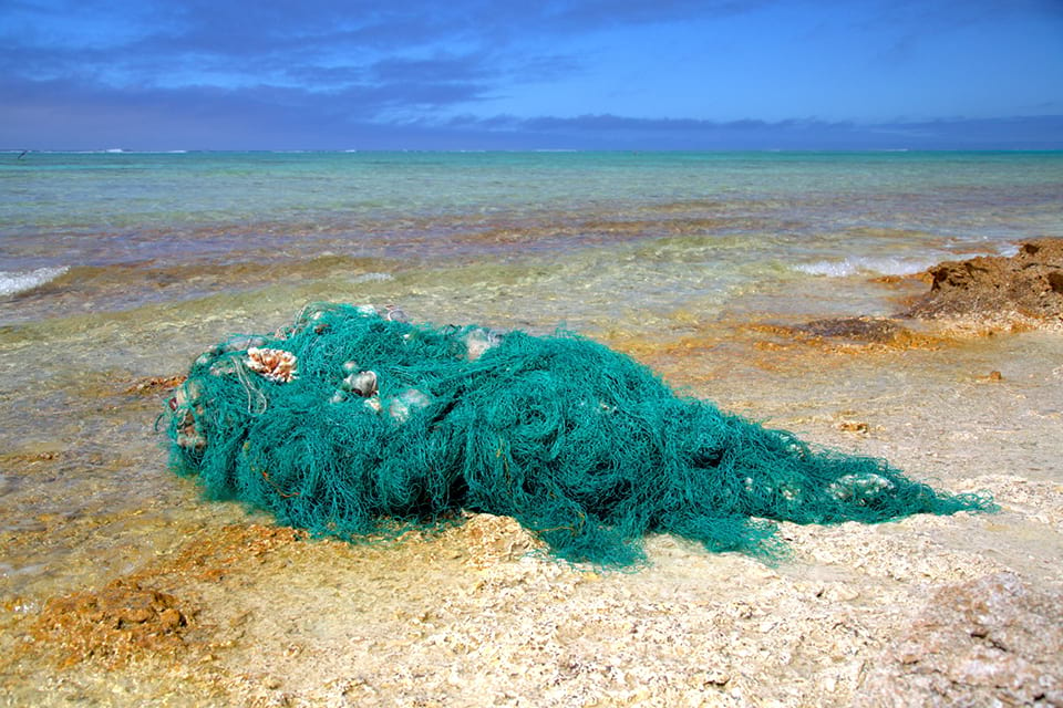 Image of a fishing net that has become marine debris bundled up on a beach
