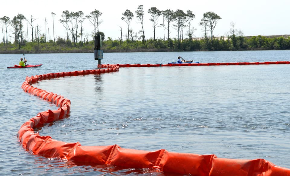 Kayakers at Naval Air Station Pensacola detour around oil containment boom on base at Sherman Cove , Pensacola, Florida, on May 4, 2010.