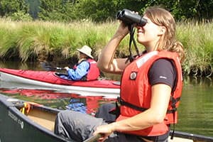 women in a canoe looking through binoculars