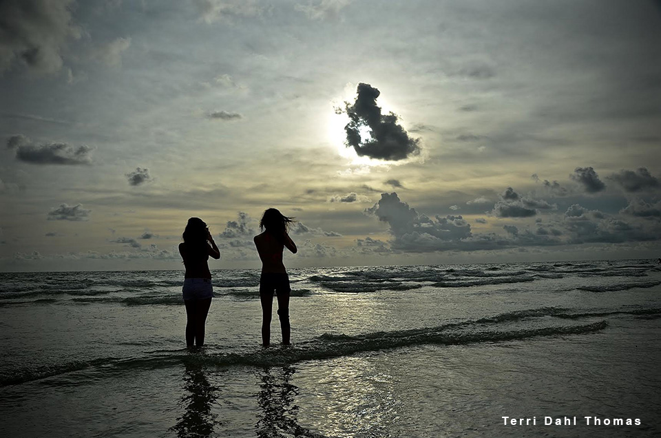 women standing on beach at sunset