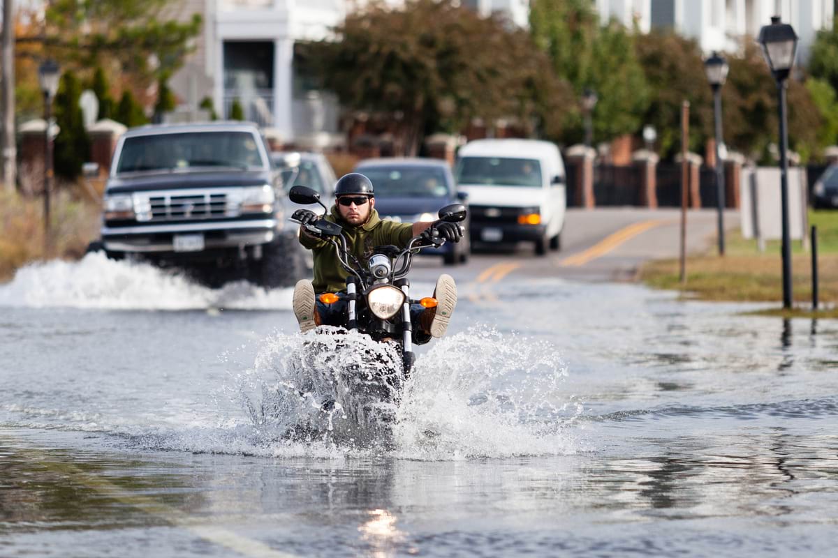 Motorists crossing a flooded street in a low-lying Norfolk neighborhood called Colonial Place, which floods at every high tide.