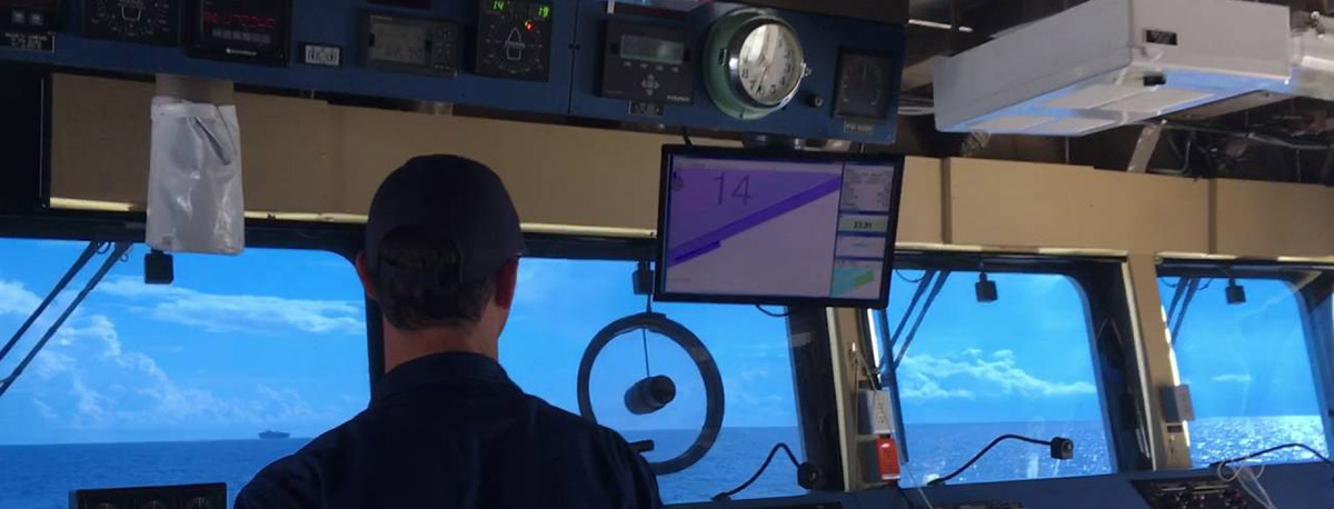View of a man navigating a ship from the bridge.