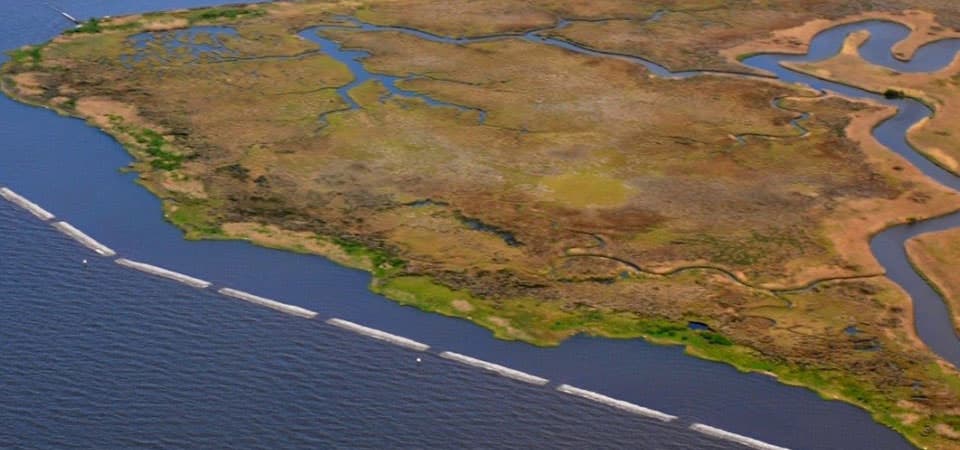 Aerial photo of the Mississippi coast with a living shoreline project that includes natural and artificial breakwater material and marsh creation to reduce shoreline erosion.