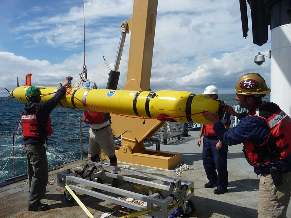 NOAA’s Office of Coast Survey's REMUS-600 Autonomous Underwater Vehicle (AUV) aboard NOAA Ship Ferdinand R. Hassler is recovered off of the coast of Maine following a seafloor mapping mission. The REMUS-600 AUV is 12 feet long, weighs 650 pounds, has an operational endurance of 24 hours, survey depth range to 500 meters, and is equipped with highly accurate positioning, navigation, and multibeam sonar systems for seafloor mapping.