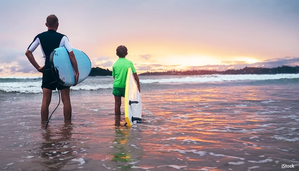 father and son about to surf on a beach